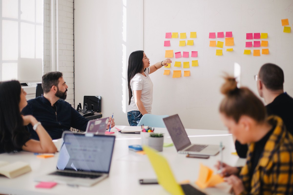 meeting room with people and post it notes on the wall - The Global Academy